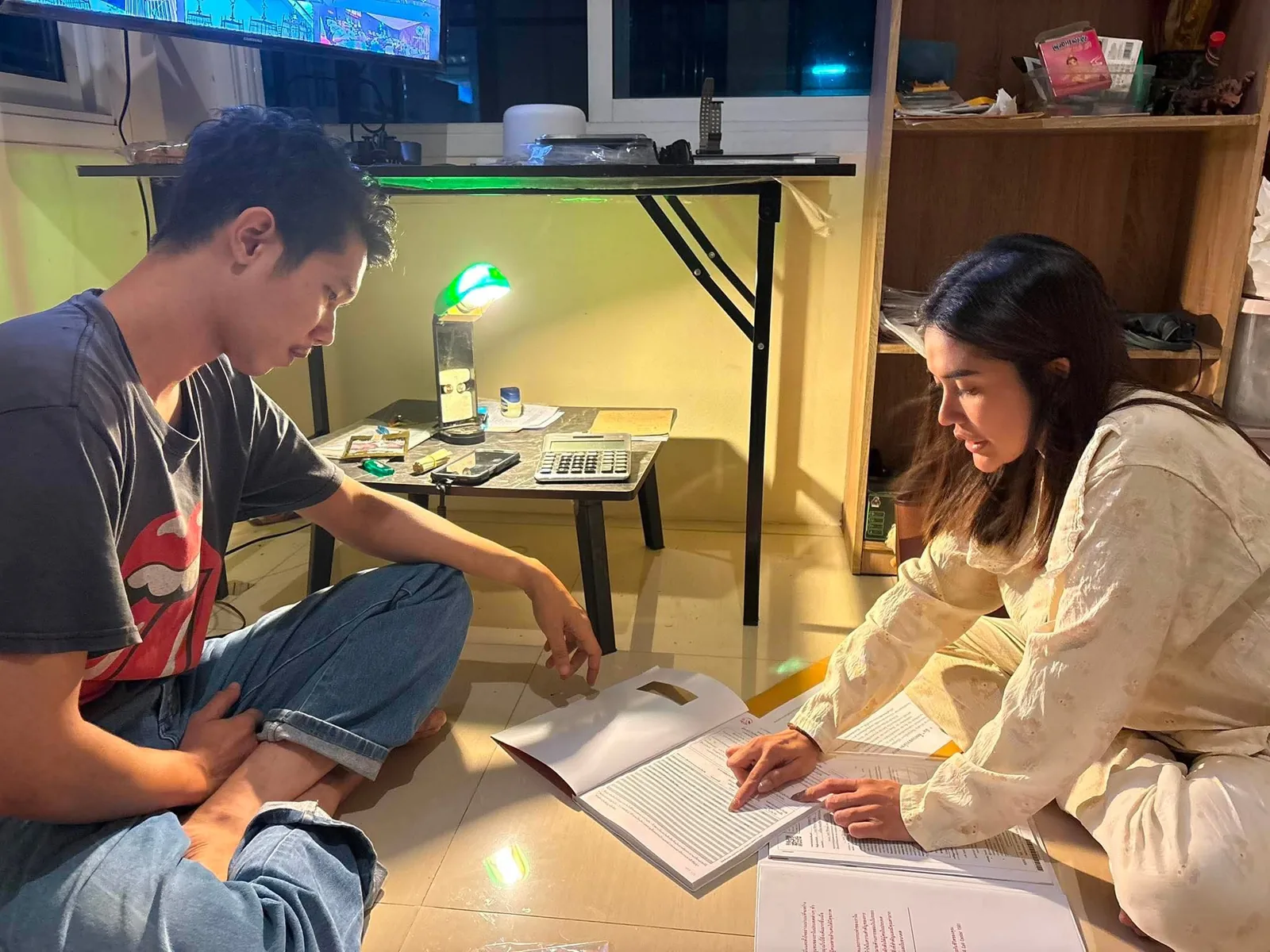 สาว วราภรณ์ กำลังนั่งอธิบายเอกสารและพูดคุยแบบเป็นกันเอง
